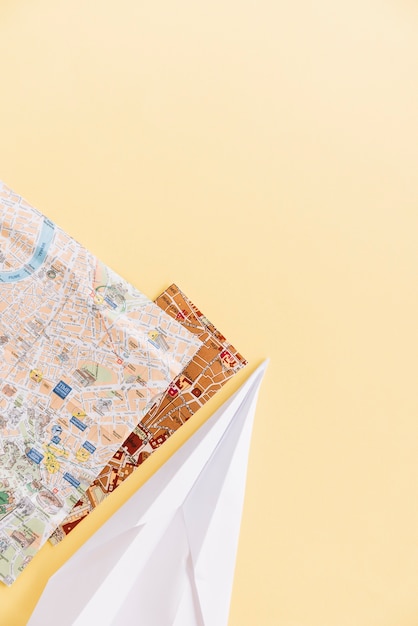 Bezpłatne zdjęcie dwie mapy miasta z ręcznie papierowym samolotem na rogu tła