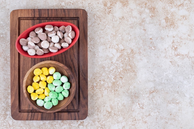 Bezpłatne zdjęcie dwie miski kolorowych cukierków na drewnianej desce