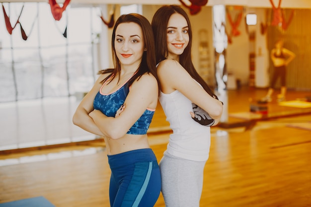 dwie młode i ładne dziewczyny w sportowym kostiumie uprawiającym sport na siłowni
