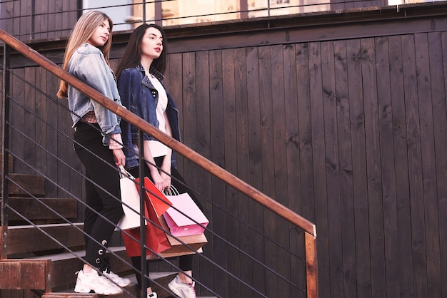 Dwie młode kobiety niosące torby na zakupy idąc po schodach po wizycie w sklepach.