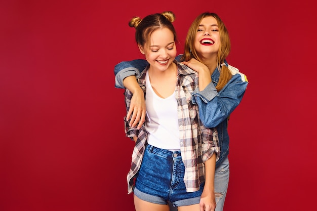 Dwie młode piękne blond uśmiechnięte hipster kobiety pozowanie w modne letnie kraciaste koszule ubrania