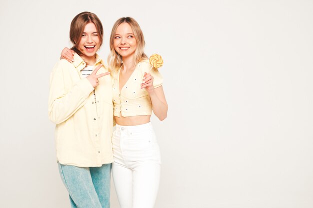 Dwie młode piękne blond uśmiechnięte hipsterki w modnych letnich ubraniach
