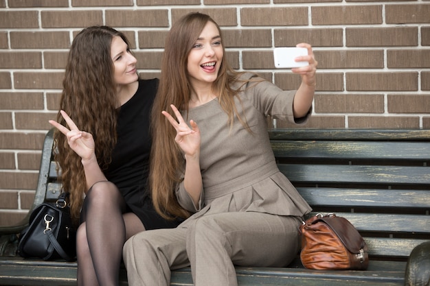 Bezpłatne zdjęcie dwie młode piękne kobiety biorąc selfie na ulicy