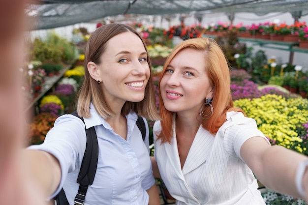 Dwie Młode Piękne Panie Co Selfie Na Tle Kwiatów W Szklarni