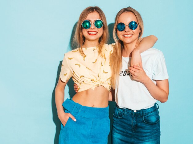 Dwie młode piękne uśmiechnięte blond hipster dziewczyny w modne letnie dżinsy spódnice ubrania.