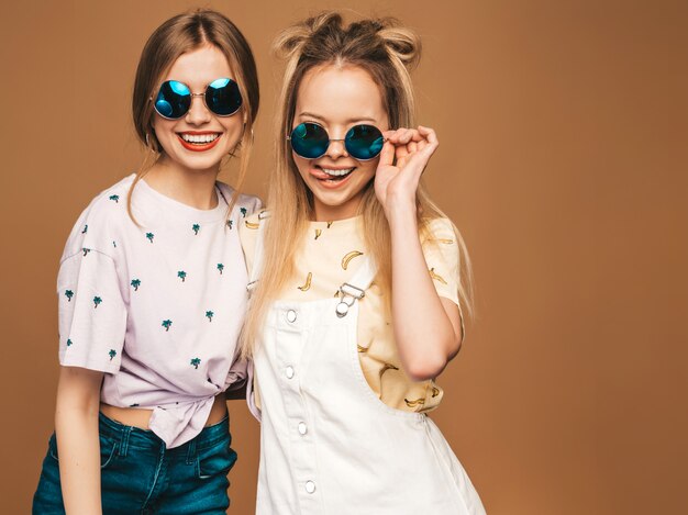 Dwie młode piękne uśmiechnięte blond hipster dziewczyny w modne letnie kolorowe ubrania T-shirt.