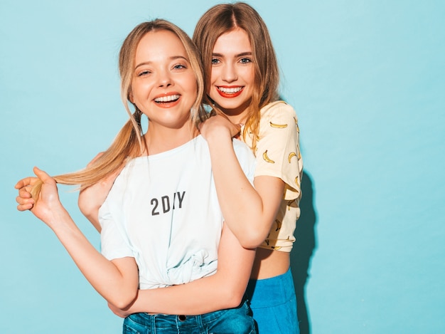 Bezpłatne zdjęcie dwie młode piękne uśmiechnięte blond hipster dziewczyny w modne letnie kolorowe ubrania t-shirt.