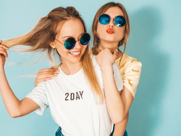 Dwie młode piękne uśmiechnięte blond hipster dziewczyny w modne letnie kolorowe ubrania T-shirt.