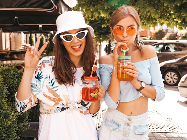 Bezpłatne zdjęcie dwie młode piękne uśmiechnięte dziewczyny hipster w modne letnie ubrania i kapelusz panama.