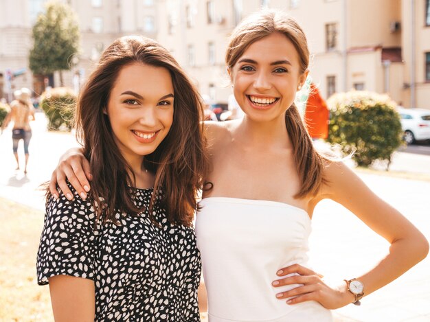 Dwie młode piękne uśmiechnięte dziewczyny hipster w modne letnie ubrania