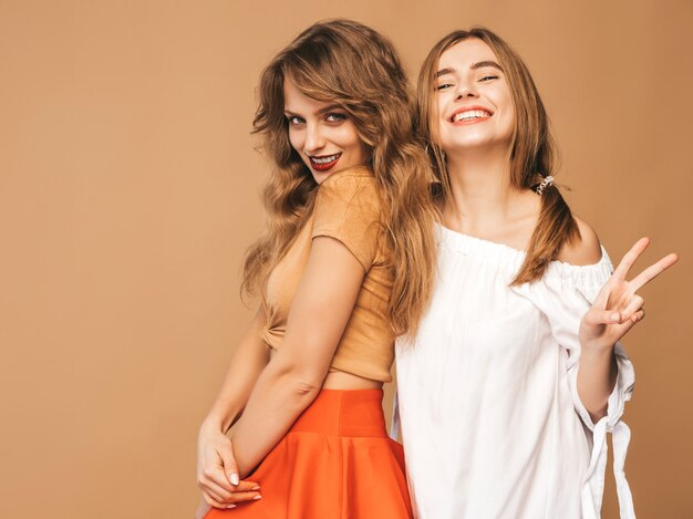 Dwie młode piękne uśmiechnięte dziewczyny w modne letnie ubrania. Seksowny beztroski kobiet pozować. Pozytywne modele pokazujące znak pokoju