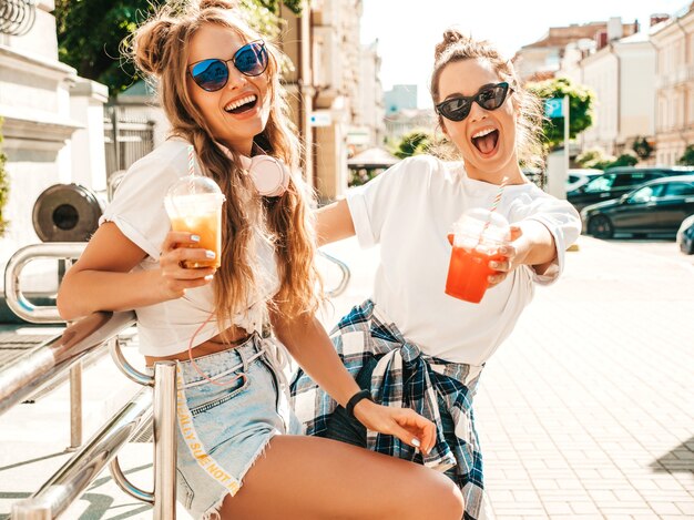 Dwie młode piękne uśmiechnięte hipsterki w modnych letnich ubraniach