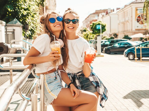 Dwie młode piękne uśmiechnięte kobiety hipster w modnych letnich ubraniach