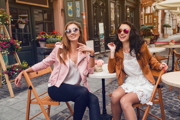 Dwie młode stylowe kobiety siedzą w kawiarni