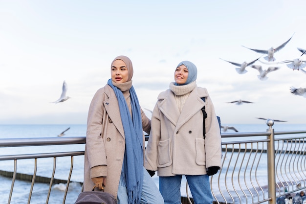 Dwie muzułmańskie koleżanki patrzące na gołębie nad oceanem podczas podróży