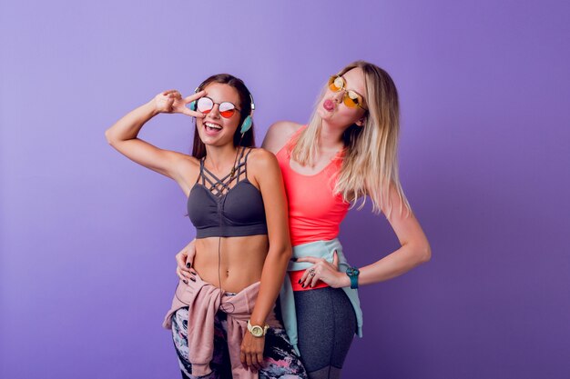 Dwie śliczne dziewczyny w modnej odzieży sportowej pozują na fioletowo