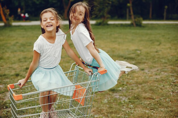 dwie urocze dziewczynki w białych koszulkach i niebieskich spódnicach grają w letnim parku