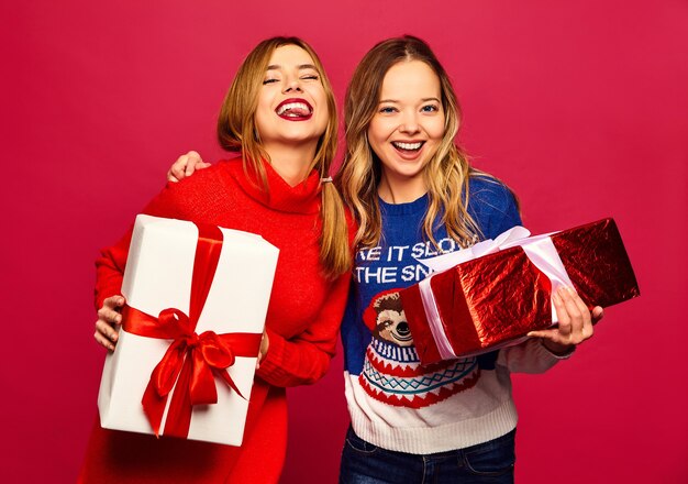 Dwie uśmiechnięte piękne kobiety w stylowych swetrach z dużymi pudełkami prezentowymi