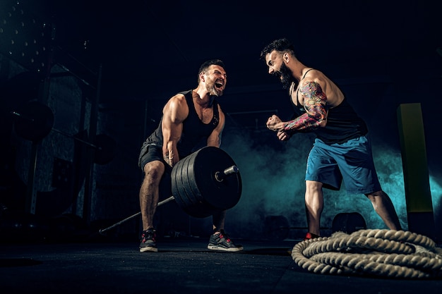 Dwóch mięśni brodaty tattoed sportowców trenujących na siłowni