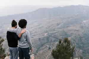 Bezpłatne zdjęcie dwóch młodych mężczyzn, patrząc na górski krajobraz