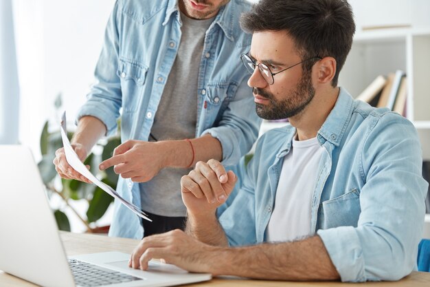 Dwóch młodych, odnoszących sukcesy pracowników biznesowych współpracuje w przestrzeni coworkingowej