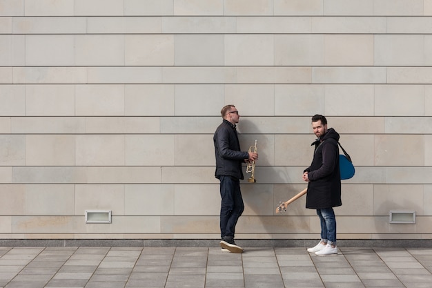 Dwóch muzyków stojących przed ścianą