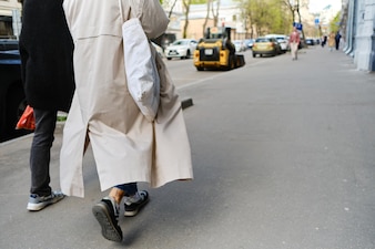 Dwóch przyjaciół idzie ulicą w chłodną pogodę płaszcz przeciwdeszczowy na wietrze jedna osoba ma ekotorbę