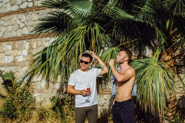 dwóch przyjaciół, młodych mężczyzn z kieliszkami szampana na tle tropikalnej zieleni