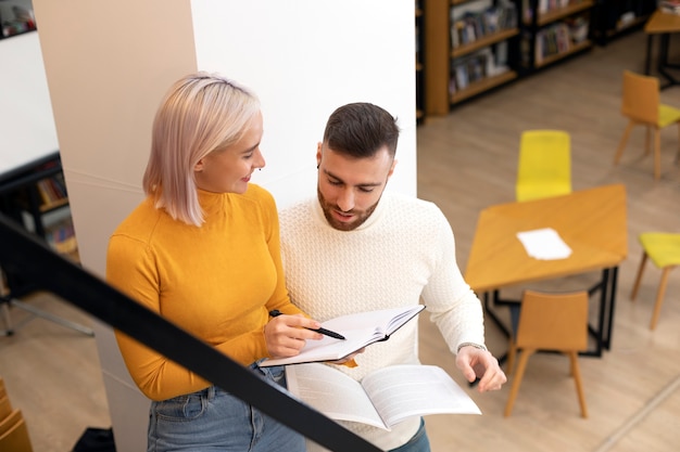 Bezpłatne zdjęcie dwoje przyjaciół szukających książek w bibliotece podczas sesji edukacyjnej