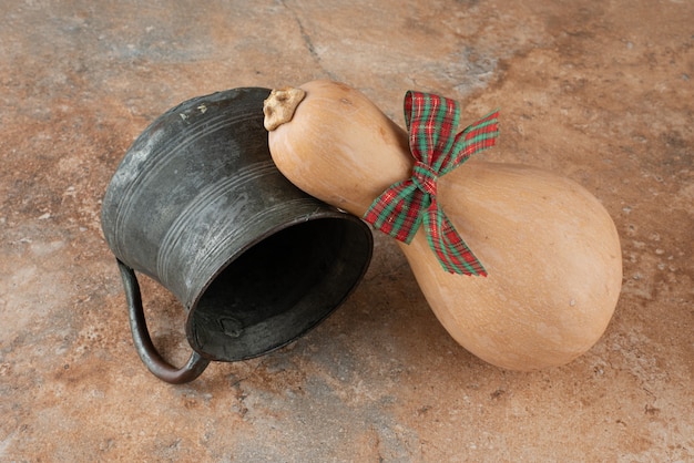 Bezpłatne zdjęcie dynia z kokardą i starożytnym czajnikiem na marmurze.