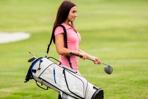 Bezpłatne zdjęcie dysponowana młoda kobieta niesie kije golfowych
