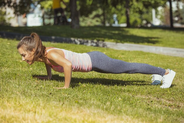 Bezpłatne zdjęcie dysponowana sprawności fizycznej kobieta robi rozciąganiu ćwiczy outdoors w parku