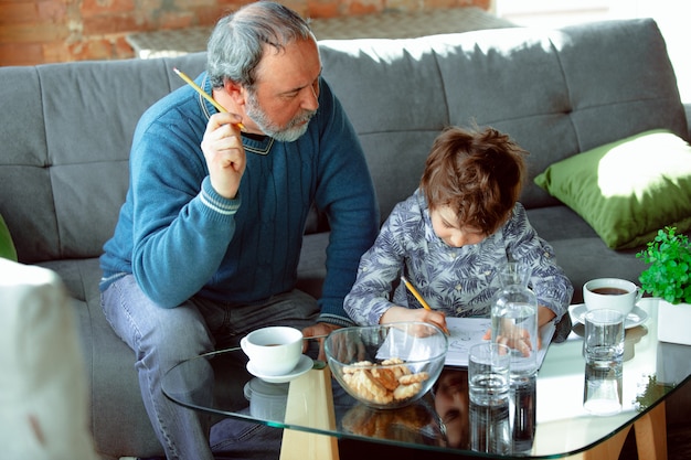 Bezpłatne zdjęcie dziadek i jego wnuk spędzają czas w domu izolując się, studiując