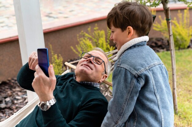 Dziadek na zewnątrz z wnuczką trzymającą telefon
