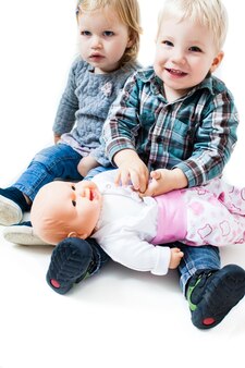 Dzieci bawiące się lalkami. chłopiec i dziewczynki siedzą na podłodze w przedszkolu i bawią się w rodzinę. pojęcie ojcostwa