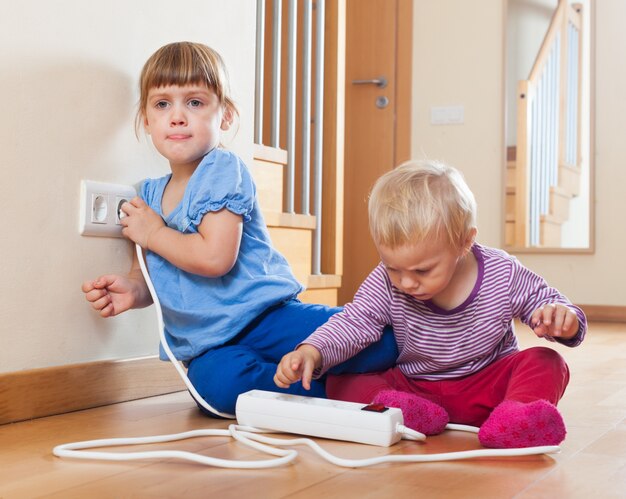 dzieci bawiące się przedłużeniem i wylotem elektrycznym