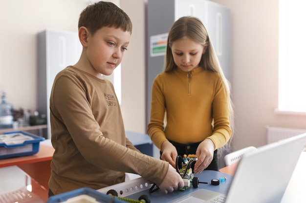 Bezpłatne zdjęcie dzieci budują robota przy użyciu części elektronicznych