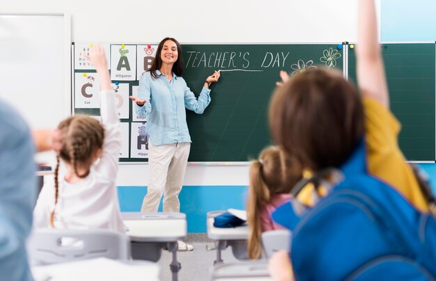 Dzieci chcące odpowiedzieć na pytanie nauczyciela