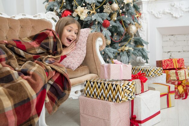 Dzieci cieszą się wakacjami. pokonaj gorączkę świąteczną. poranek przed bożym narodzeniem. mała dziewczynka. choinka i prezenty. szczęśliwego nowego roku. zima. świąteczne zakupy online. rodzinne wakacje.