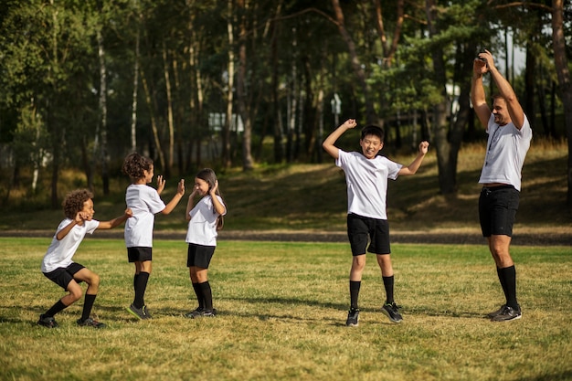 Bezpłatne zdjęcie dzieci grające w piłkę pod okiem trenera piłki nożnej