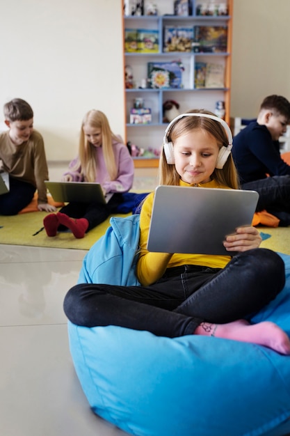 Dzieci korzystające z tabletu i laptopa do pracy i słuchania muzyki
