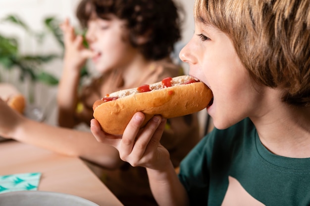 Dzieci razem jedzą hot dogi