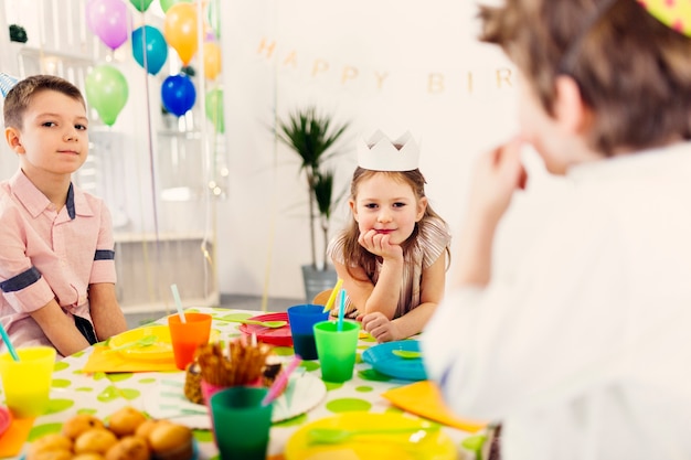 Bezpłatne zdjęcie dzieci w kolorowe czapki siedzi przy stole