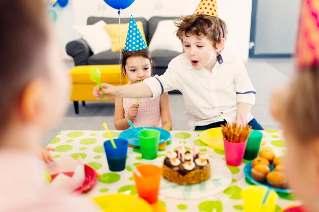 Dzieci w kolorowych czapkach jedzących przekąski
