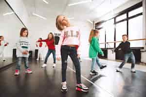 Bezpłatne zdjęcie dzieci w szkole tańca. tancerze baletowi, hiphopowi, street, funky i nowocześni na tle studia.