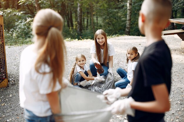 Dzieci zbierają śmieci w workach na śmieci w parku