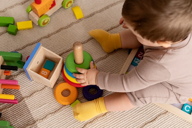 Dzieciak bawiący się kolorowymi zabawkami pod wysokim kątem