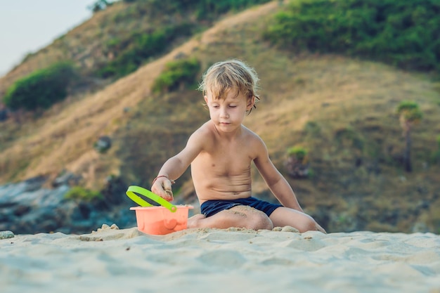 Dzieciak bawiący się na brzegu morza z łopatą i wiadrem