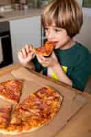 Bezpłatne zdjęcie dziecko je pizzę w domu