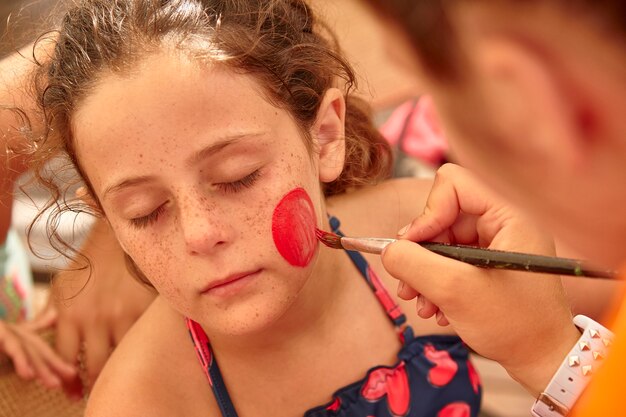 Dziecko jest pomalowane na twarzy na letnią imprezę